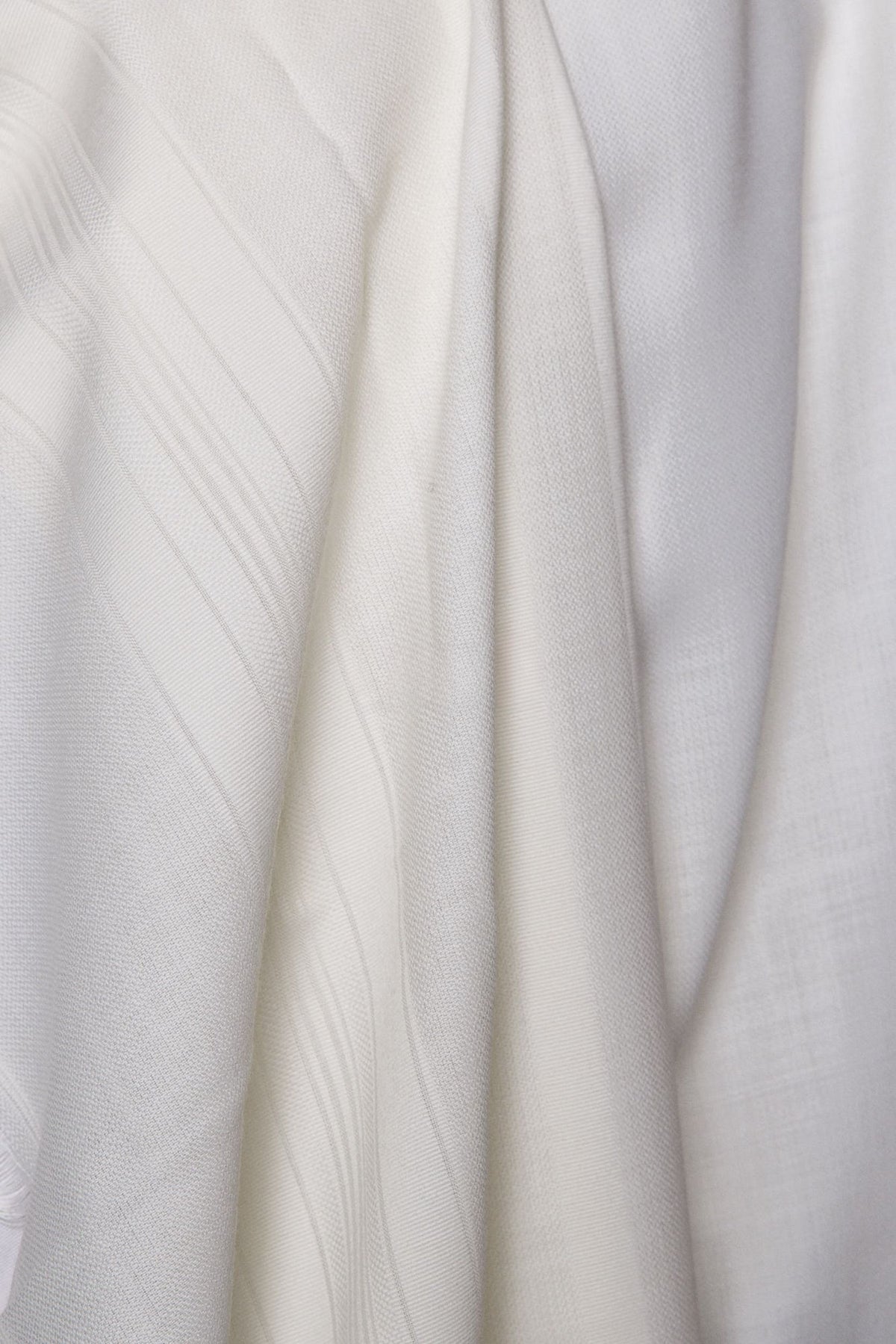 Yishtabach non-slip wool tallit draped over the shoulders, showing the white Beit Yosef stripes